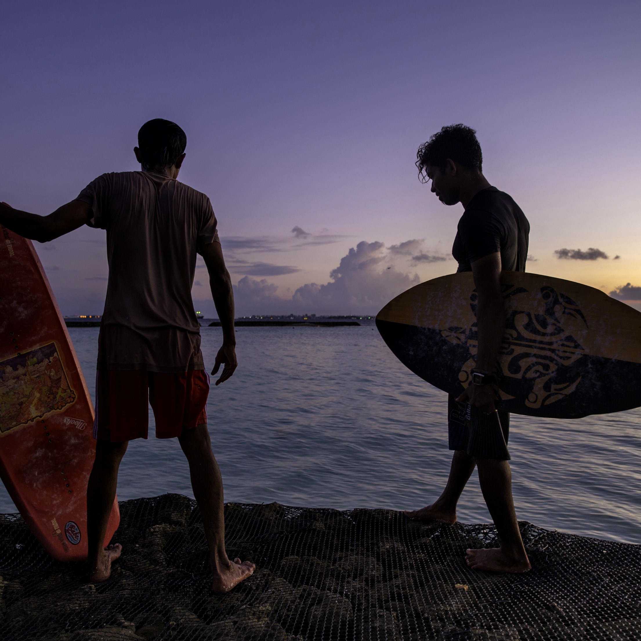 surfers at sunset in the maldives