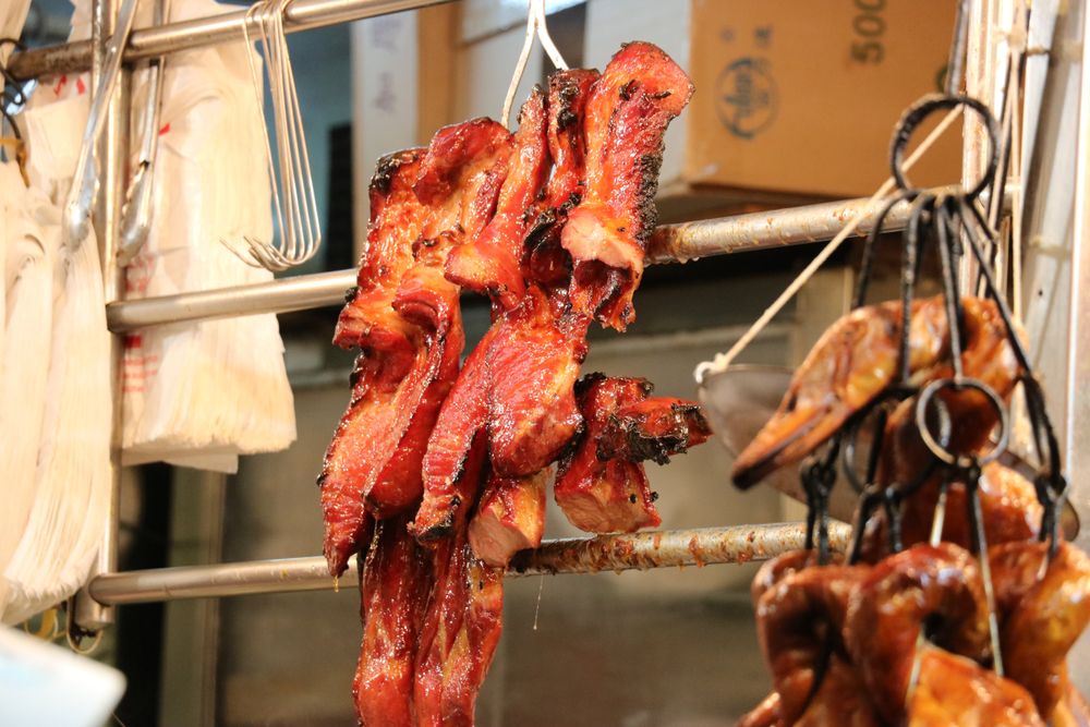 barbecued pork hanging from a food stall